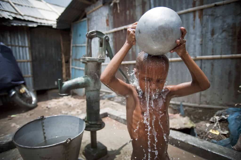 A young boy is pouring water over himself